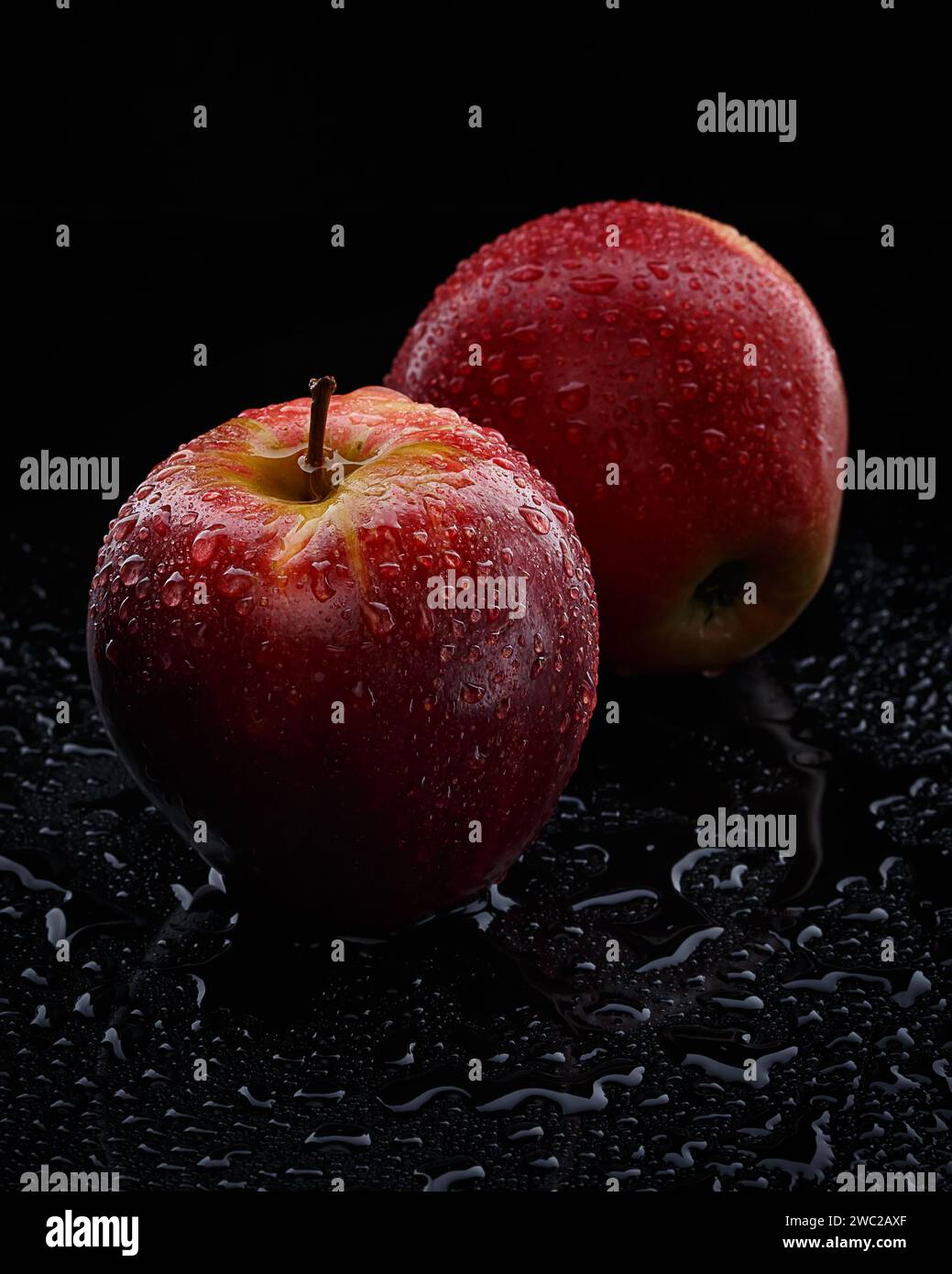 2 mele rosse con gocce d'acqua su sfondo nero Foto Stock