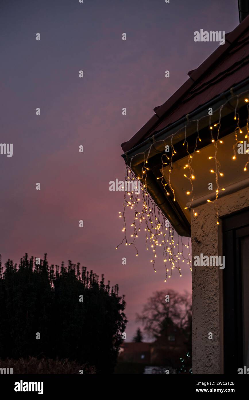 Luci natalizie illuminano una casa durante un tramonto rosa, Berlino, Germania, Europa Foto Stock