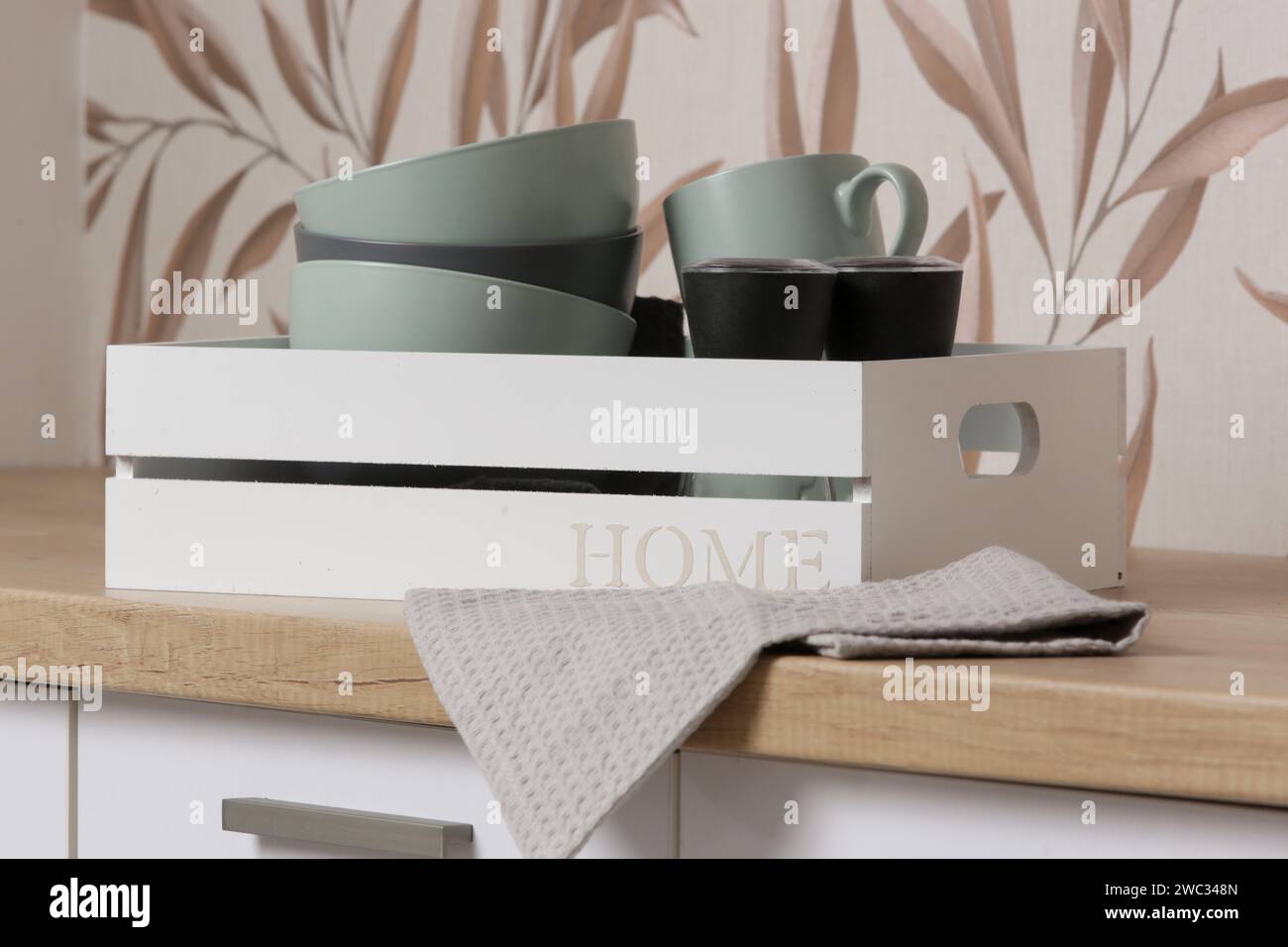 Ciotole e tazze in ceramica nella scatola di legno sul bancone della cucina, concetto di organizzazione della vita domestica Foto Stock