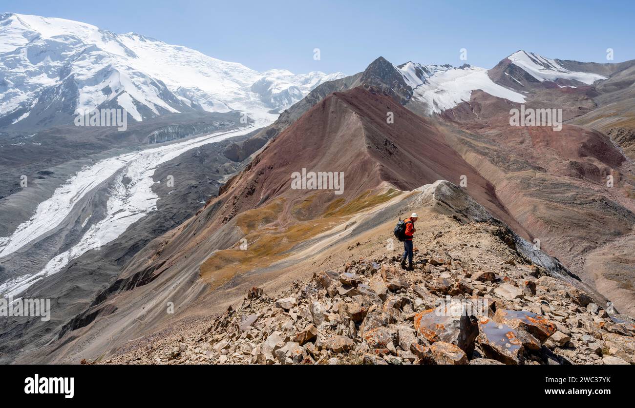 Alpinista al Traveller's Pass con vista dell'impressionante paesaggio montano, del paesaggio di alta montagna con morene del ghiacciaio e lingue del ghiacciaio Foto Stock