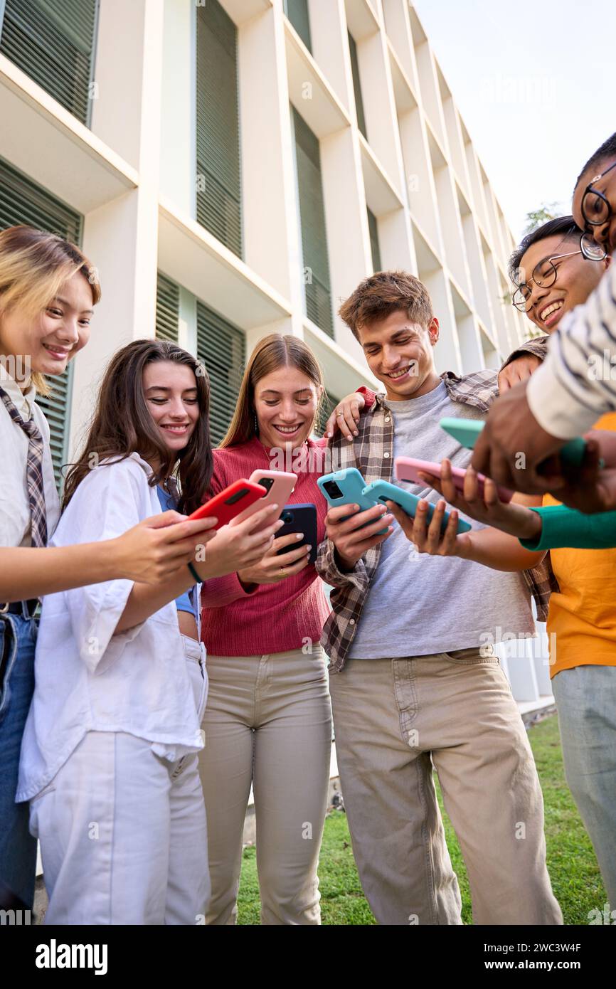 Gruppo di generazioni multirazziali z giovani sorridono volentieri guardando video divertenti su uno smartphone Foto Stock