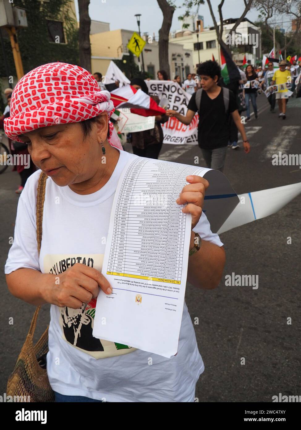 Lima, Perù. 13 gennaio 2024. Manifestante con una lunga lista con i nomi delle vittime della guerra a Gaza quando decine di persone sono scese in piazza a Lima per manifestare come parte di una marcia globale per la Palestina. Si uniscono a milioni di persone che marceranno in più di 66 città, in almeno 36 paesi, in una giornata globale d’azione per la Palestina. Credito: Agenzia stampa Fotoholica/Alamy Live News Foto Stock