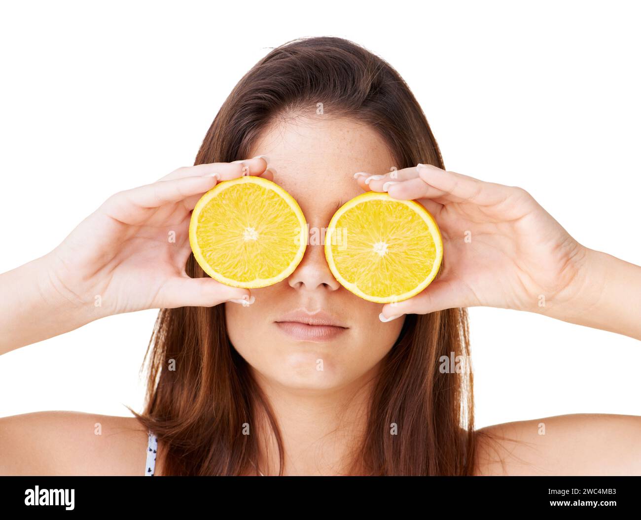 La donna ricopre il viso con frutti d'arancia in studio per disintossicarsi, dieta vegana e dermocosmesi naturale per nutrirsi su sfondo bianco. Ragazza seria, agrumi e.. Foto Stock