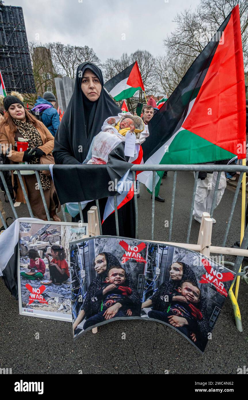 Una donna palestinese con bambola che rappresenta un bambino di Gaza, durante l'udienza della Corte internazionale di giustizia (ICJ). Centinaia di sostenitori pro-palestinesi e alcuni pro-israeliani sono stati tenuti ben separati oggi, al di fuori della Corte internazionale di giustizia (ICJ) o del Palazzo della Pace dell'Aia, il secondo giorno dell'udienza. Il Sudafrica ha accusato Israele di genocidio nei confronti del popolo palestinese. Oggi, gli israeliani hanno avuto la possibilità di difendersi in tribunale e hanno respinto con veemenza le accuse come "infondate” e antisemite. A Gaza, più di 23.800 persone - per lo più donne e.. Foto Stock