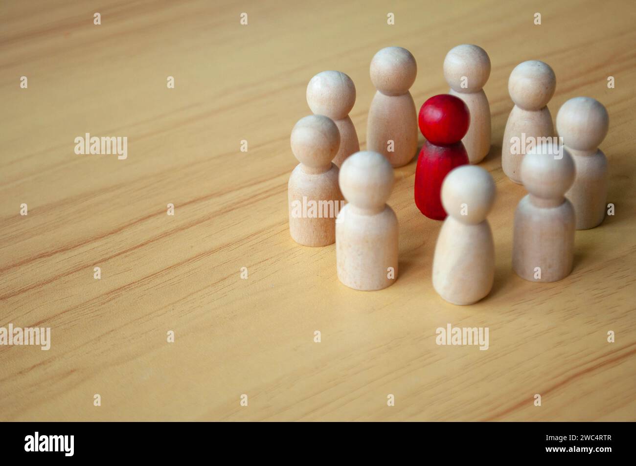 Bambola di legno rossa circondata da altre bambole. Rappresentare discussioni, leadership o molestie. Foto Stock