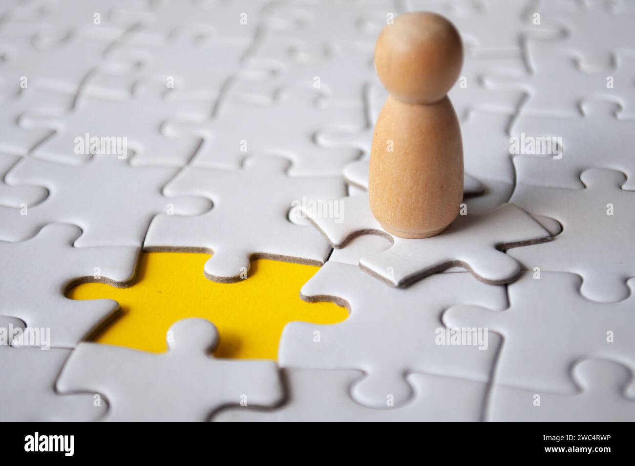 Bambola in legno sopra il puzzle con puzzle mancante. Concetto di assunzione e occupazione. Foto Stock