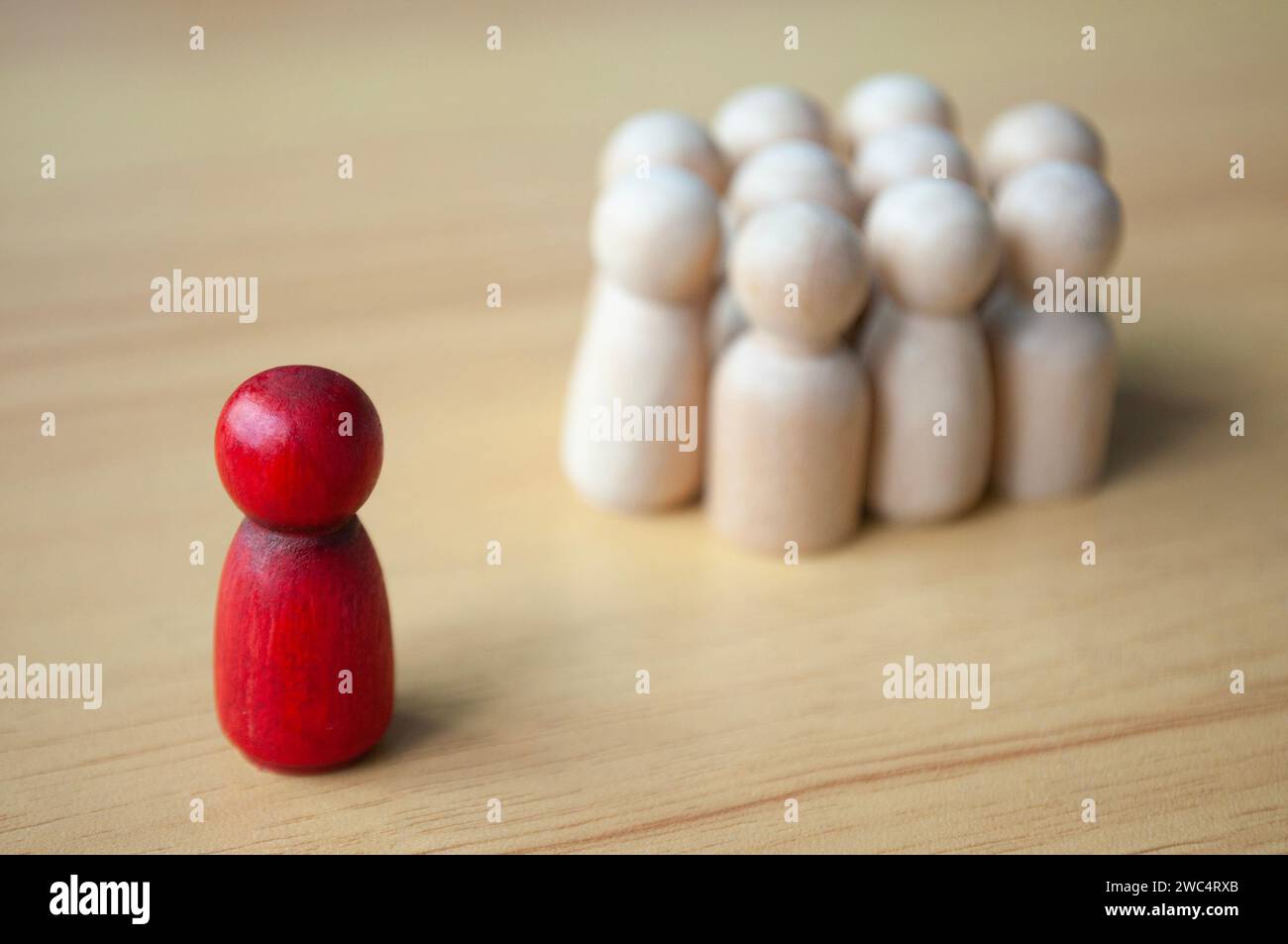 Una singola bambola di legno rossa separata da altre bambole. Rappresentare la leadership o l'isolamento. Foto Stock