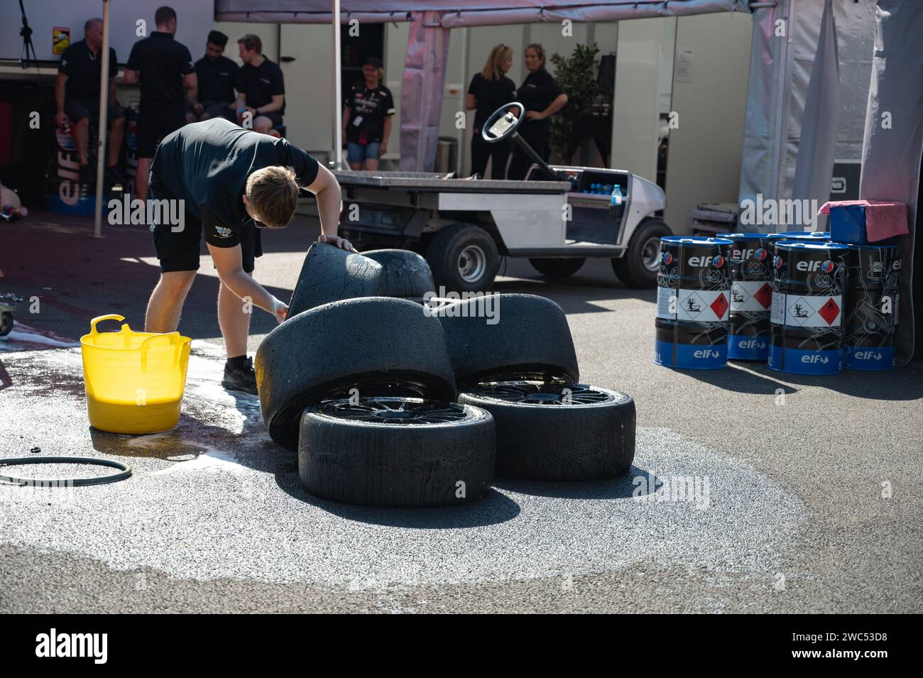 Un ragazzo che pulisce le gomme da corsa con una spugna, sapone e acqua. Foto Stock