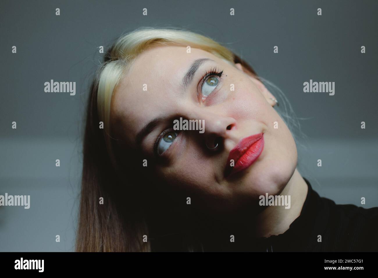 Una donna splendida con capelli fluenti e lussureggianti e accattivanti occhi blu guarda tranquillamente in lontananza Foto Stock