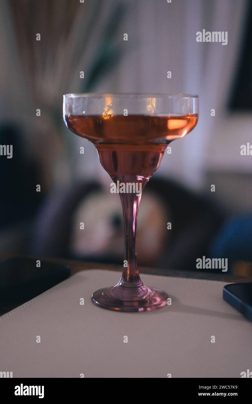 Un elegante vetro riempito con un liquido arancione brillante posizionato su un elegante tavolo Foto Stock