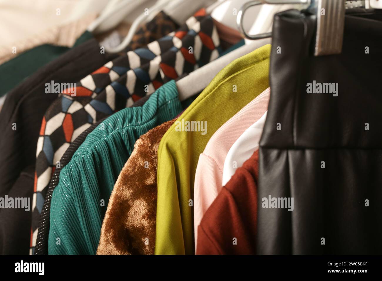 Moda femminile. Vestiti diversi sugli appendiabiti, primo piano. Ampia scelta di abiti da donna usati sul portapacchi in un negozio di seconda mano o in un negozio di articoli da regalo Foto Stock