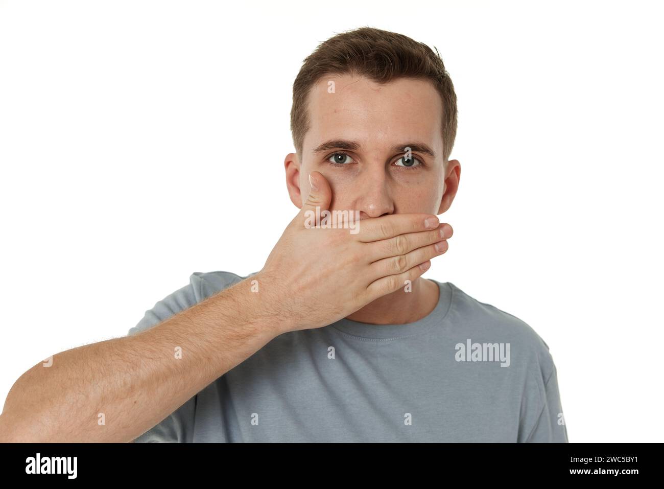uomo che copre la bocca con le mani su sfondo bianco Foto Stock