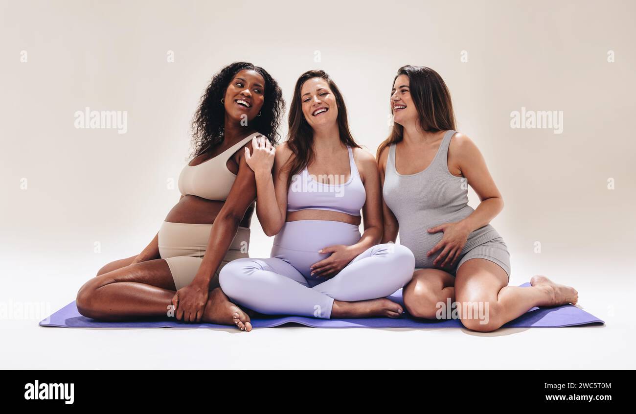 Gruppo di donne incinte che si riuniscono per una lezione di fitness prenatale. Praticano yoga ed esercizio fisico, promuovendo la cura di sé e il benessere durante la pregna Foto Stock