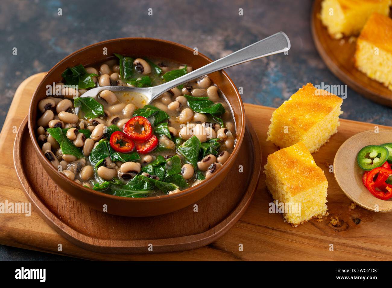 Piselli dell'occhio nero del sud e verdure di collarino in una ciotola marrone con pane di mais Foto Stock
