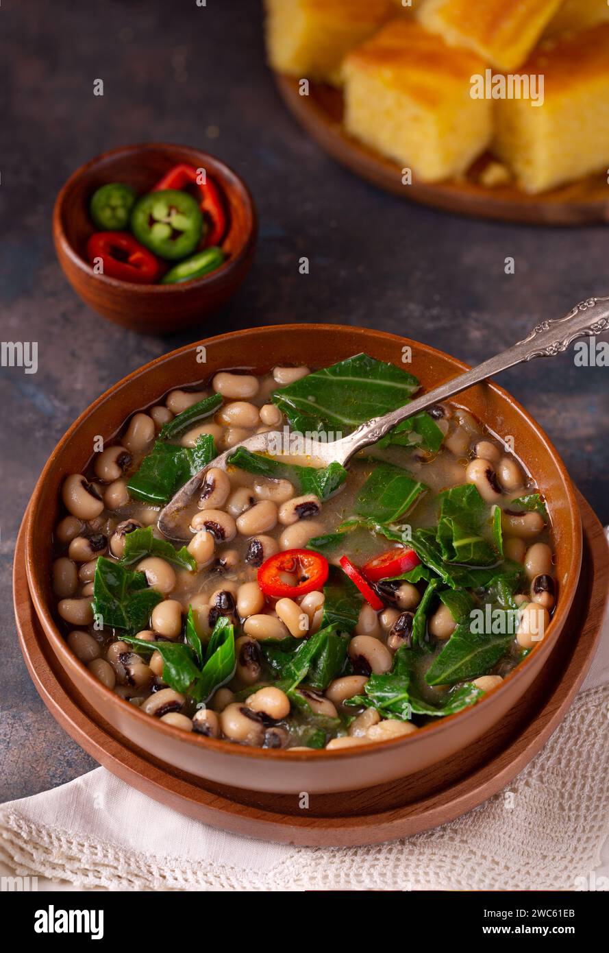 Piselli neri del sud DEGLI STATI UNITI e collarino verde in una ciotola marrone con pane di mais sullo sfondo Foto Stock