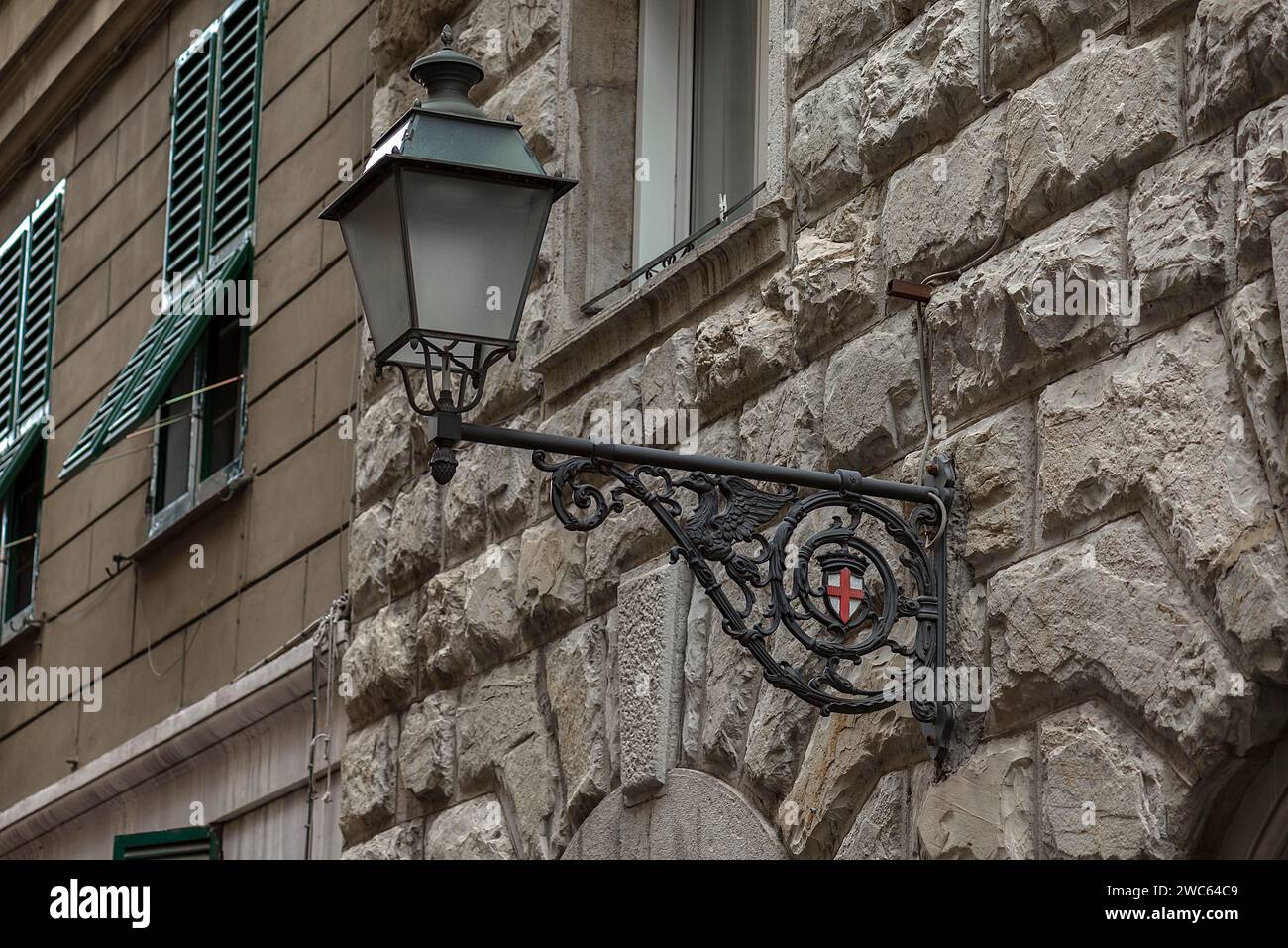 Vecchio lampione su un muro di casa con lo stemma della città, Genova, Italia Foto Stock