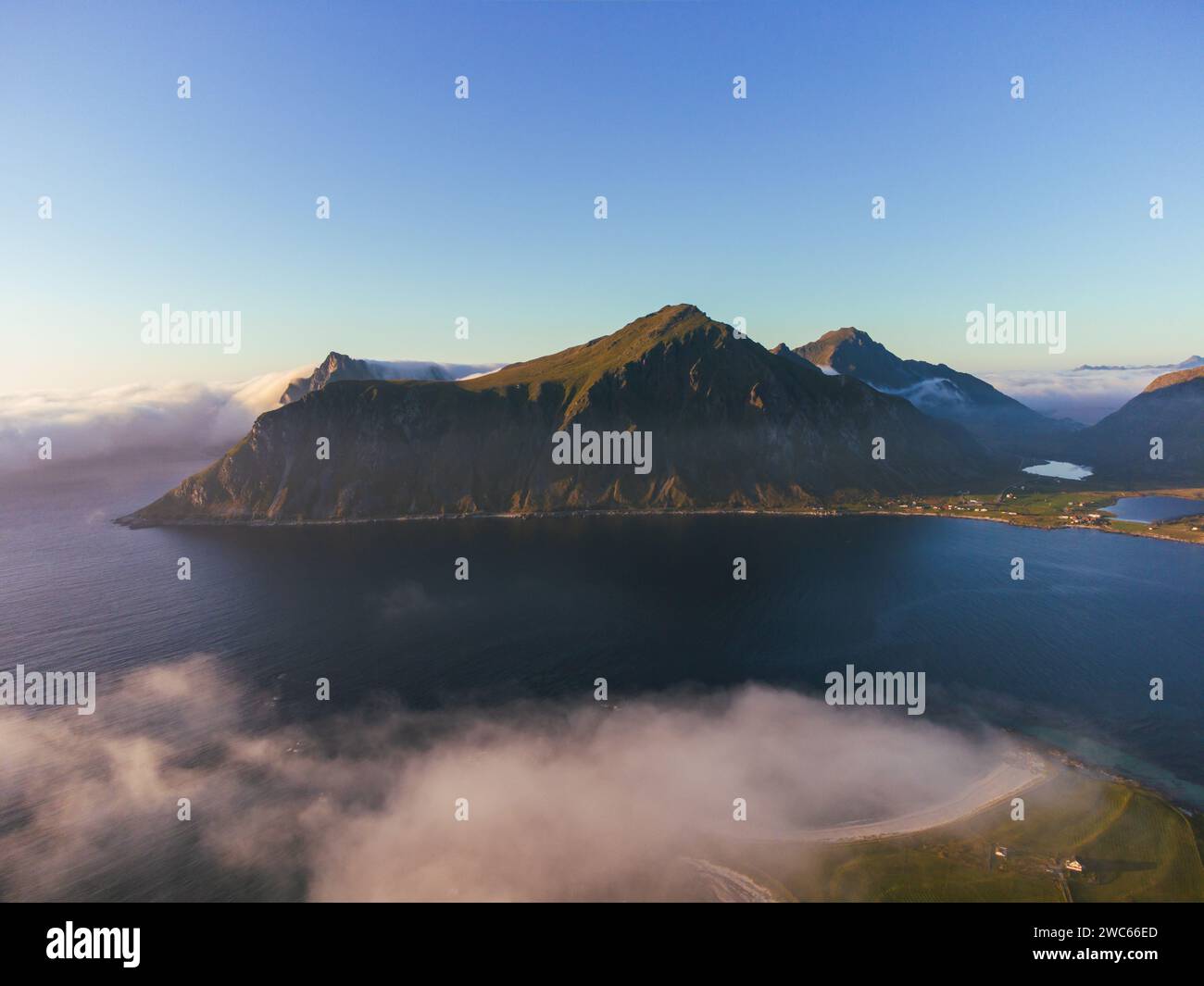 Vista aerea del Lofoten al tramonto, con spettacolari montagne, profondi fiordi e cielo blu con nebbia macchiata. Foto Stock
