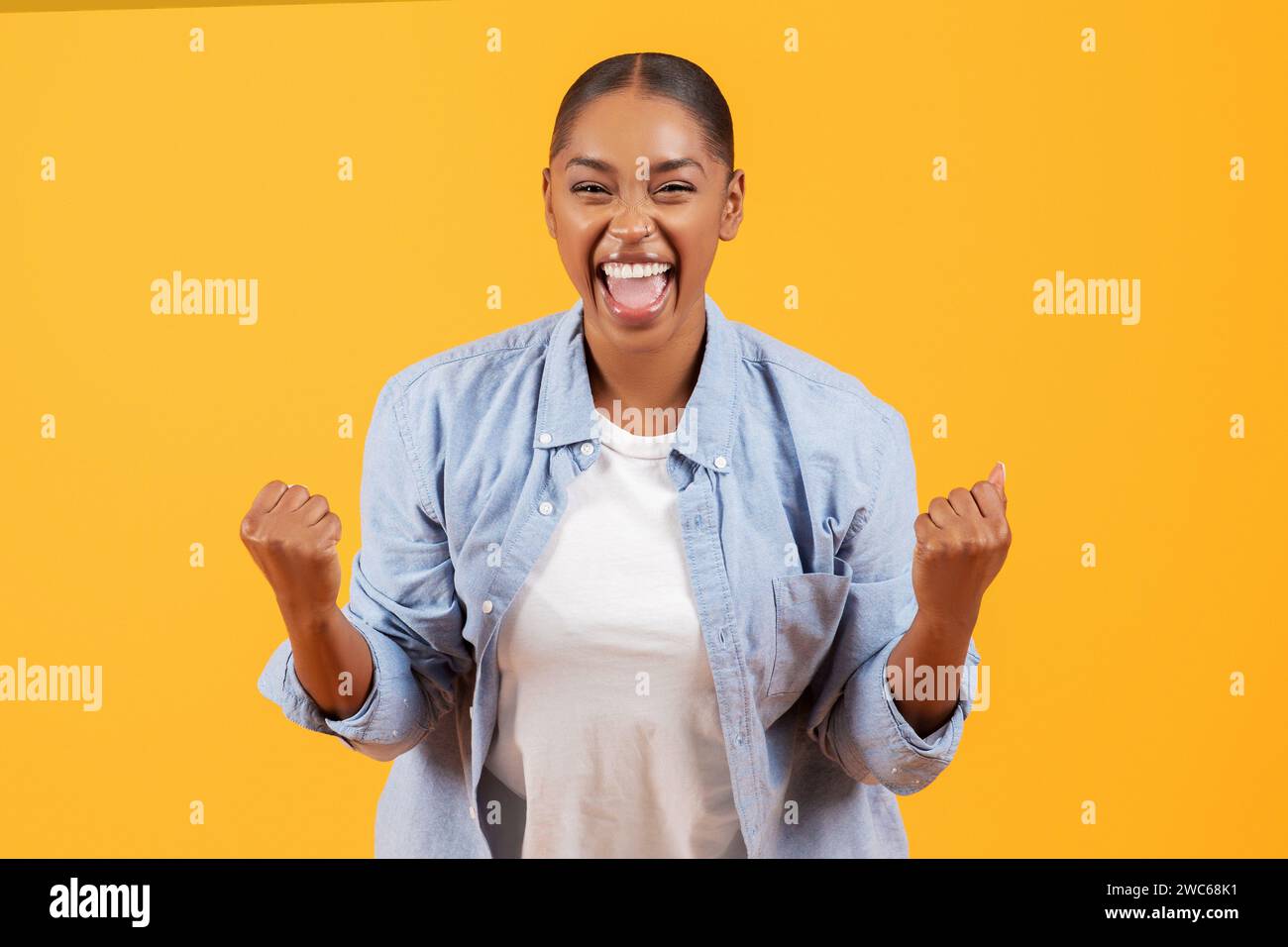 Una donna nera allegra ed emotiva che fa il tifo e urla a pugni tremolanti, studio Foto Stock