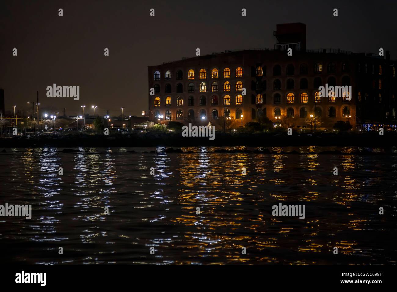 Vecchi edifici del molo Red Hook con luci notturne e riflessi in acqua, Brooklyn, New York Foto Stock