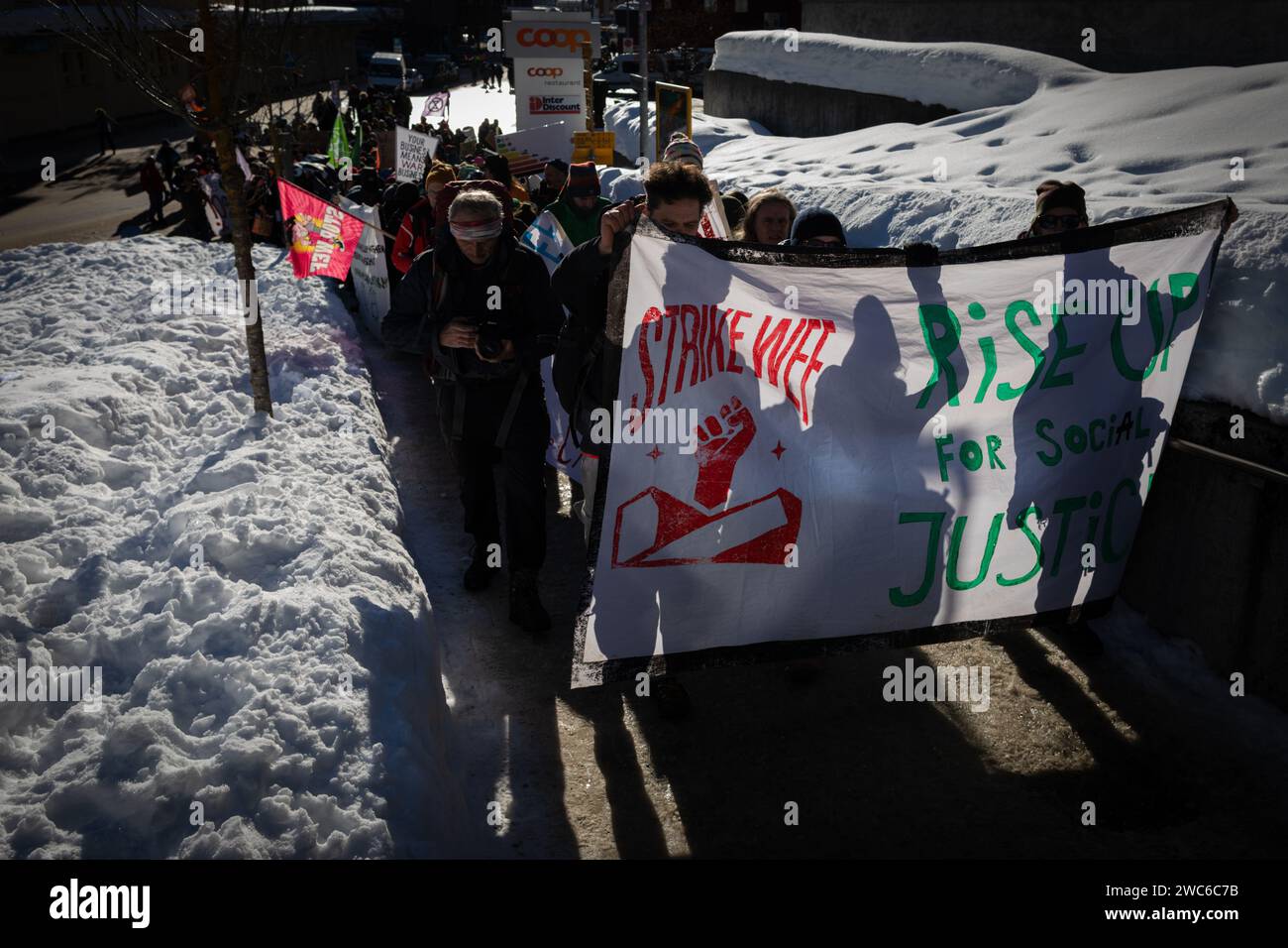 Davos, Svizzera. 14 gennaio 2024. Davos, CH 14 gennaio 2024. I manifestanti portano uno striscione a Davos per protestare contro il 54° Forum economico Mondiale. Centinaia di manifestanti si sono riuniti per esprimere preoccupazioni sull'agenda del WEF di quest'anno. Il Forum coinvolge i leader politici, commerciali e culturali della società per definire i programmi globali, regionali e industriali, che possono avere un impatto su tutti in tutto il mondo. Crediti: Andy Barton/Alamy Live News Foto Stock