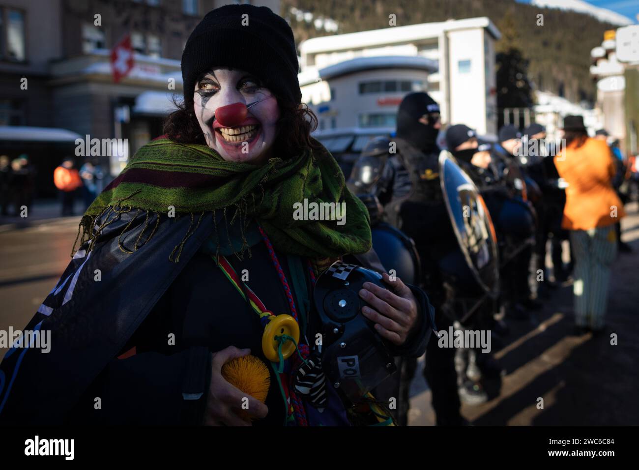 Davos, Svizzera. 14 gennaio 2024. Davos, CH 14 gennaio 2024. Un manifestante vestito da clown viene fermato da un cordone della polizia durante il 54° Forum economico Mondiale. Centinaia di manifestanti si sono riuniti per esprimere preoccupazioni sull'agenda del WEF di quest'anno. Il Forum coinvolge i leader politici, commerciali e culturali della società per definire i programmi globali, regionali e industriali, che possono avere un impatto su tutti in tutto il mondo. Crediti: Andy Barton/Alamy Live News Foto Stock