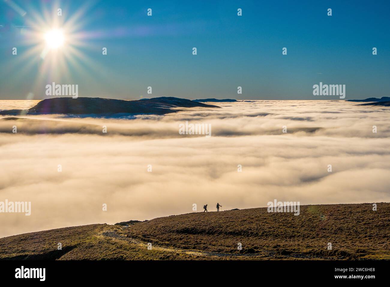 Camminatori in collina che camminano sopra un mare di nuvole nel Lake District National Park Foto Stock