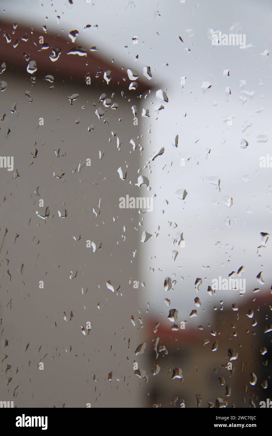 Una casa vista da dietro una finestra di vetro con gocce di pioggia. Foto Stock