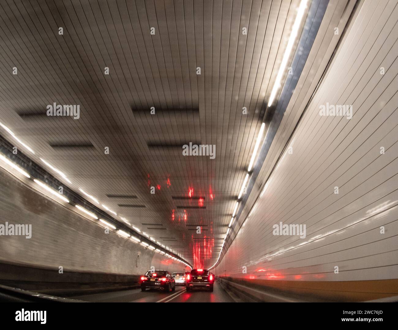 Una vista dall'interno di un tunnel che mostra un flusso di traffico affollato con numerose auto che si muovono in direzioni diverse Foto Stock