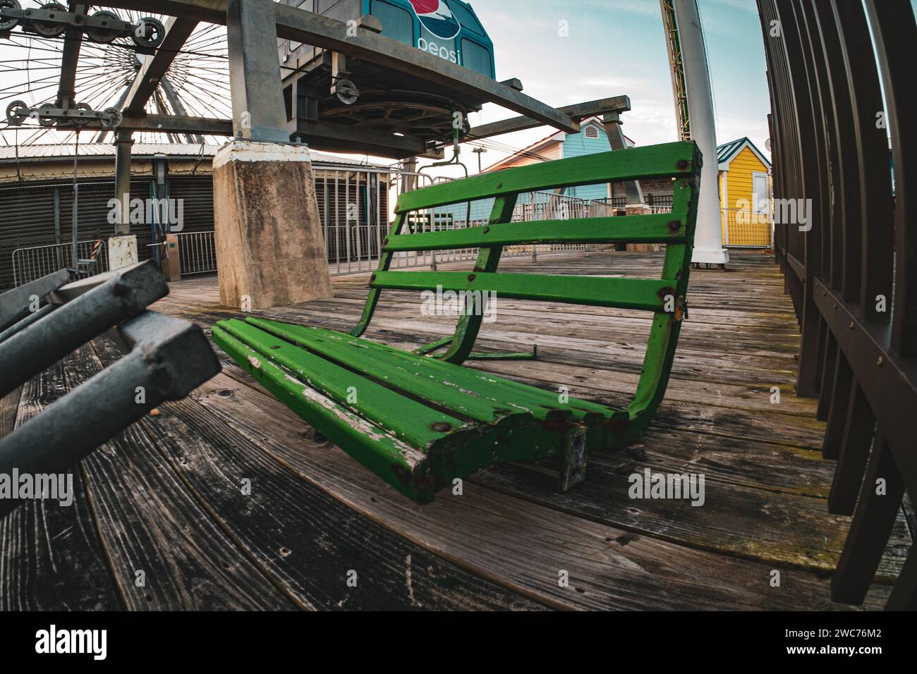 Una vibrante panchina verde si trova su un ponte di legno, affacciato su un paesaggio pittoresco con una bicicletta parcheggiata nelle vicinanze Foto Stock
