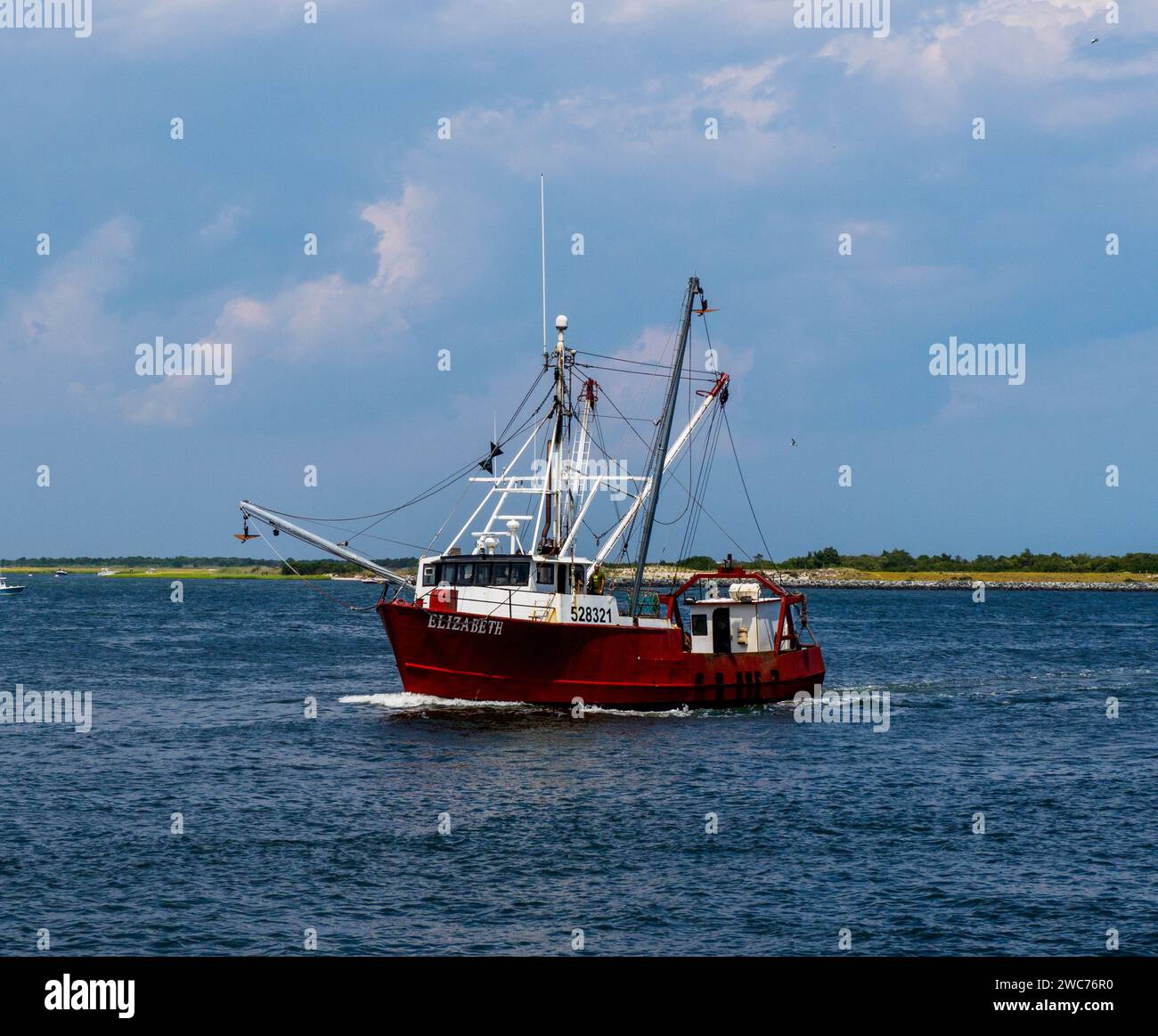 Un solitario peschereccio naviga verso una pittoresca isola sulla vasta distesa dell'oceano, creando un'affascinante scena di tranquillità e avventura Foto Stock