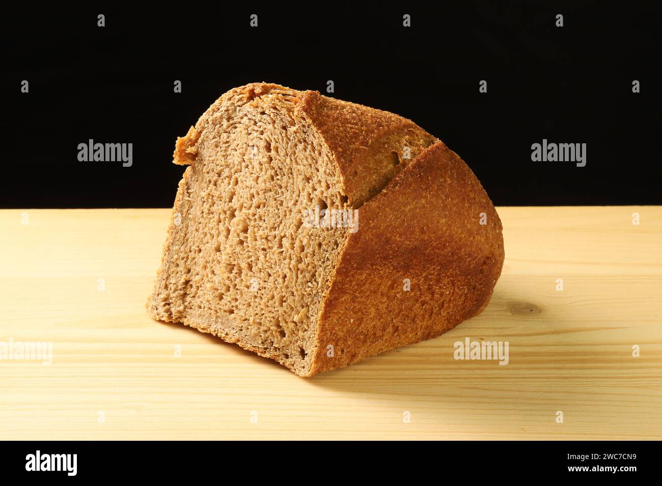 Pezzo di pane tradizionale su tavola di legno su sfondo scuro Foto Stock