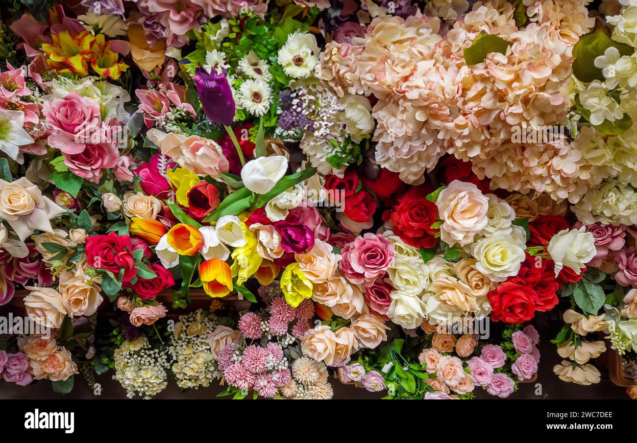 consistenza o sfondo di molti fiori artificiali mutlicolori, cornice completa di fiori Foto Stock