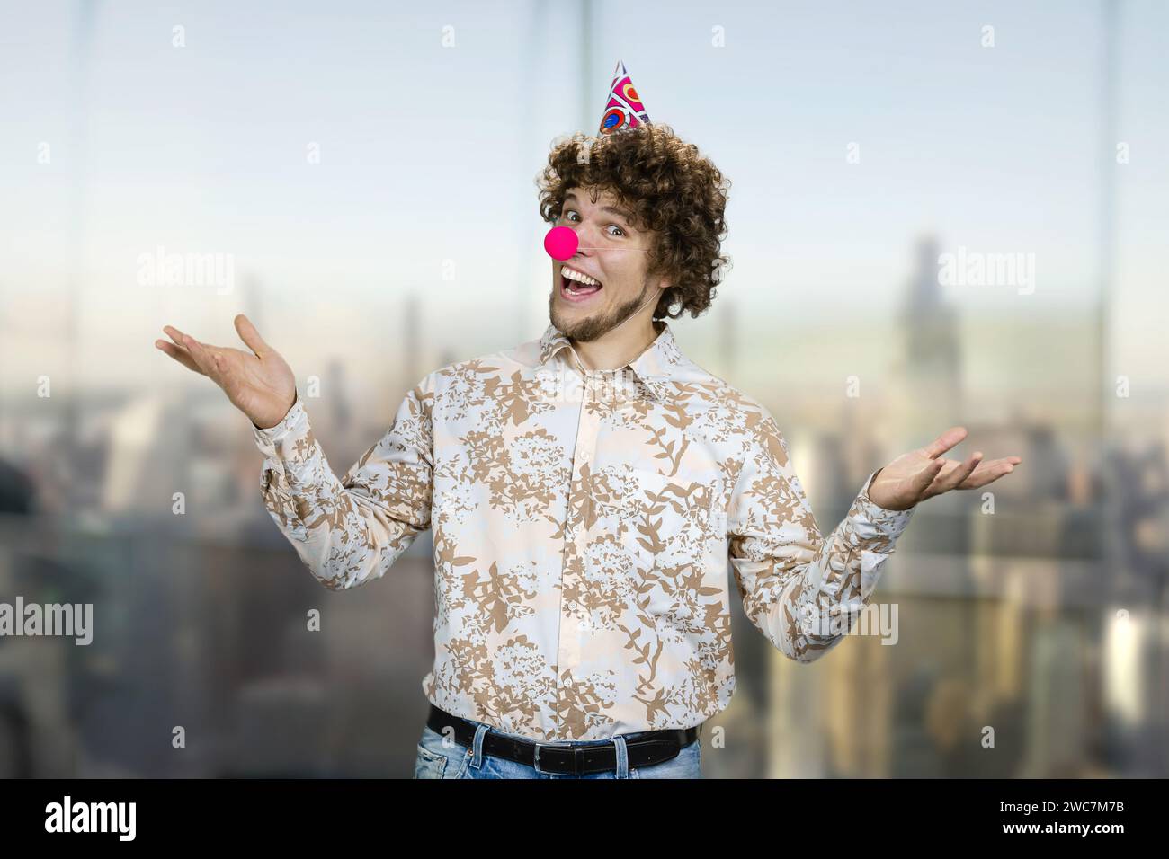 Ritratto di un giovane ragazzo caucasico con i capelli ricci che indossa il naso dei clown. Buon compleanno. Foto Stock