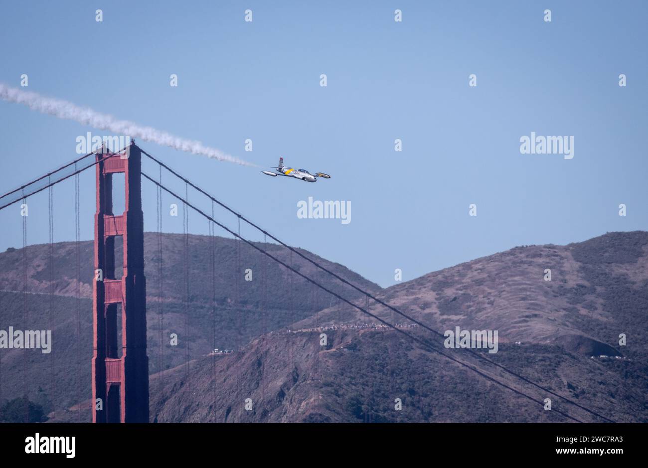 Un jet d'epoca T-33 vola a San Francisco durante uno spettacolo aereo presso il Golden Gate Bridge con le Marin Headlands e le barche a vela sullo sfondo Foto Stock