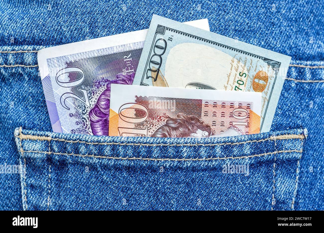 Sterline inglesi e dollari americani nella tasca posteriore dei jeans. Valuta mondiale per viaggi e shopping Foto Stock