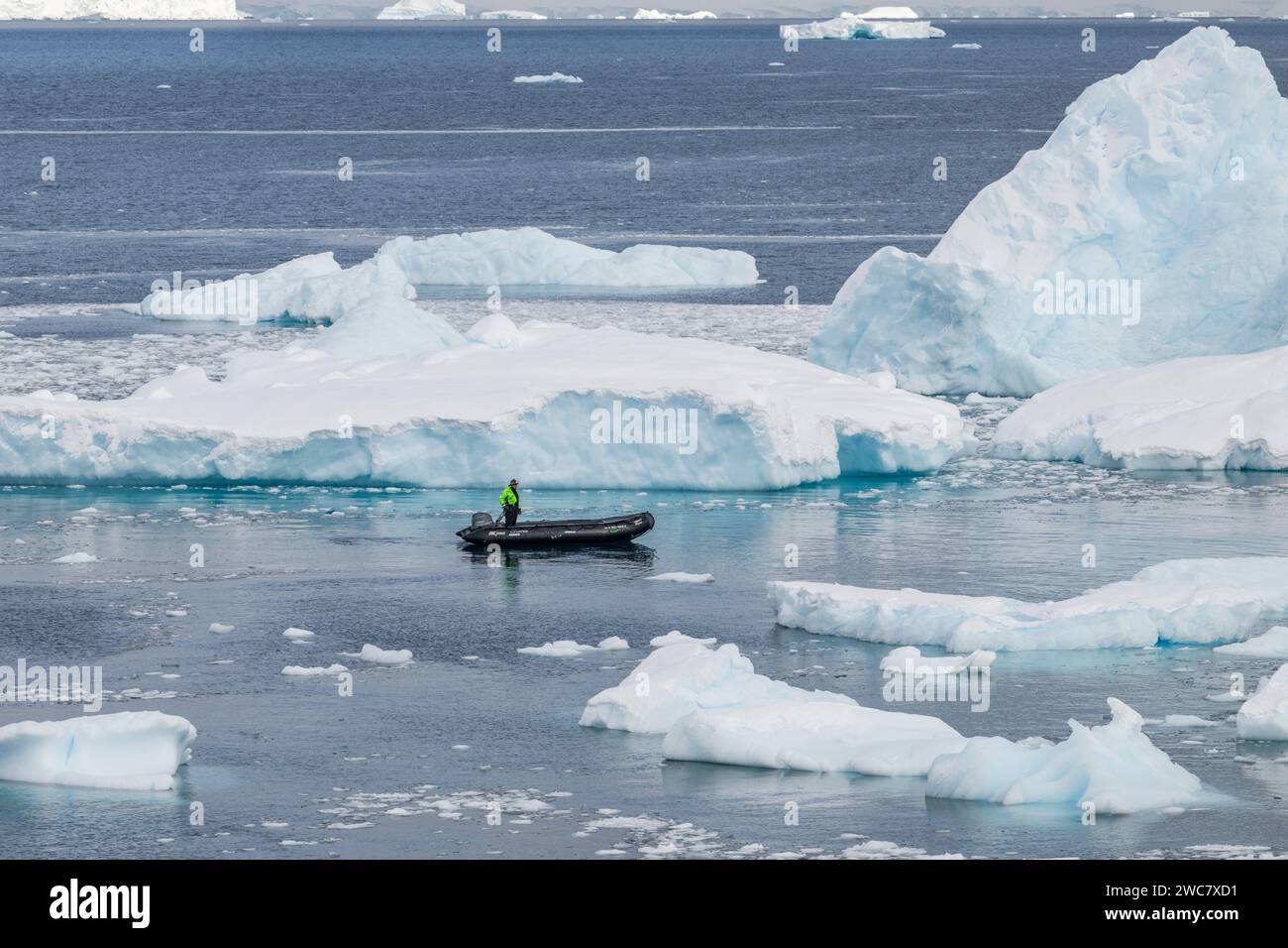 Zodiaco che naviga attraverso le acque ghiacciate di Neko, porto, Antartide, vista ravvicinata degli iceberg che si riflettono sull'acqua circostante Foto Stock