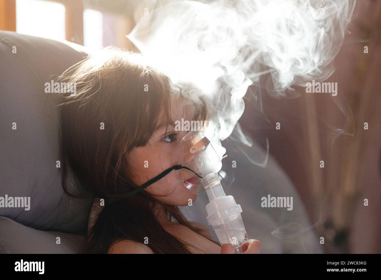 Paziente bambina con maschera inalatoria vista ravvicinata su sfondo a vapore Foto Stock