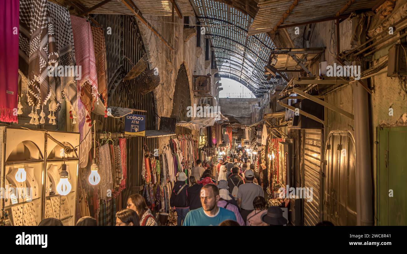 I turisti e la gente del posto camminano lungo i negozi, i negozi e le bancarelle di souvenir al Jerusalem Bazaar (mercato) nel quartiere musulmano della città vecchia, Israele Foto Stock