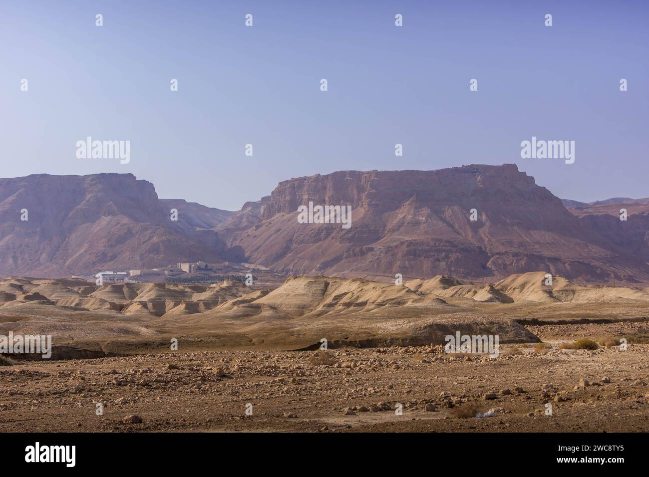 La vista dell'altopiano roccioso con il Parco Nazionale di Masada sulla sua sommità, situato sul bordo roccioso del deserto della Giudea, nella parte orientale di Israele Foto Stock