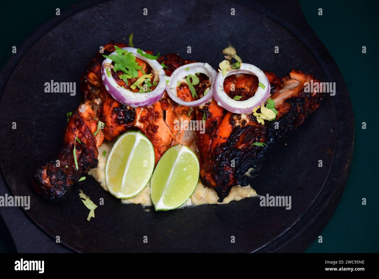 Un delizioso piatto con una generosa porzione di succulento pollo accompagnato da spicchi di lime e cipolle finemente tagliate Foto Stock