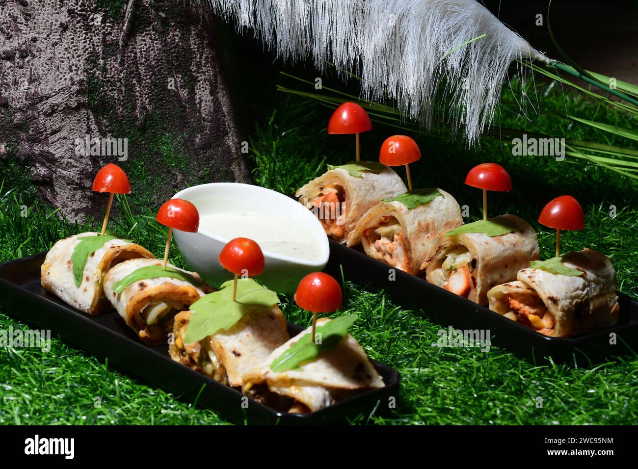 Un'appetitosa esposizione di due vassoi pieni di un delizioso assortimento di delizie culinarie diverse, completate da pomodori vivaci e maturi Foto Stock