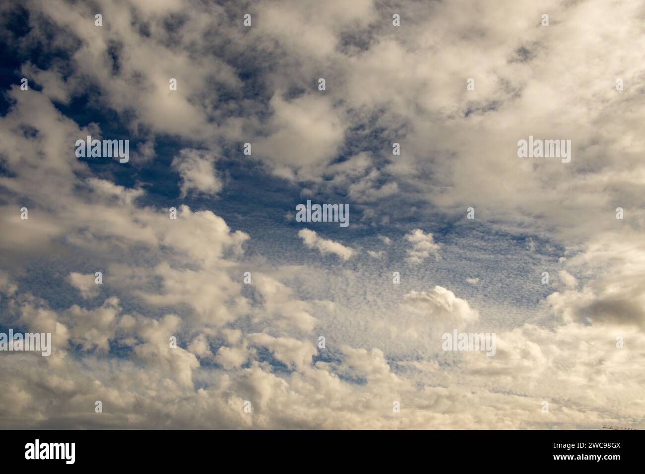 Nuvole bianche con sfondo blu. Il sole cerca di sfondare le nuvole ovali come un occhio nel cielo. Foto Stock