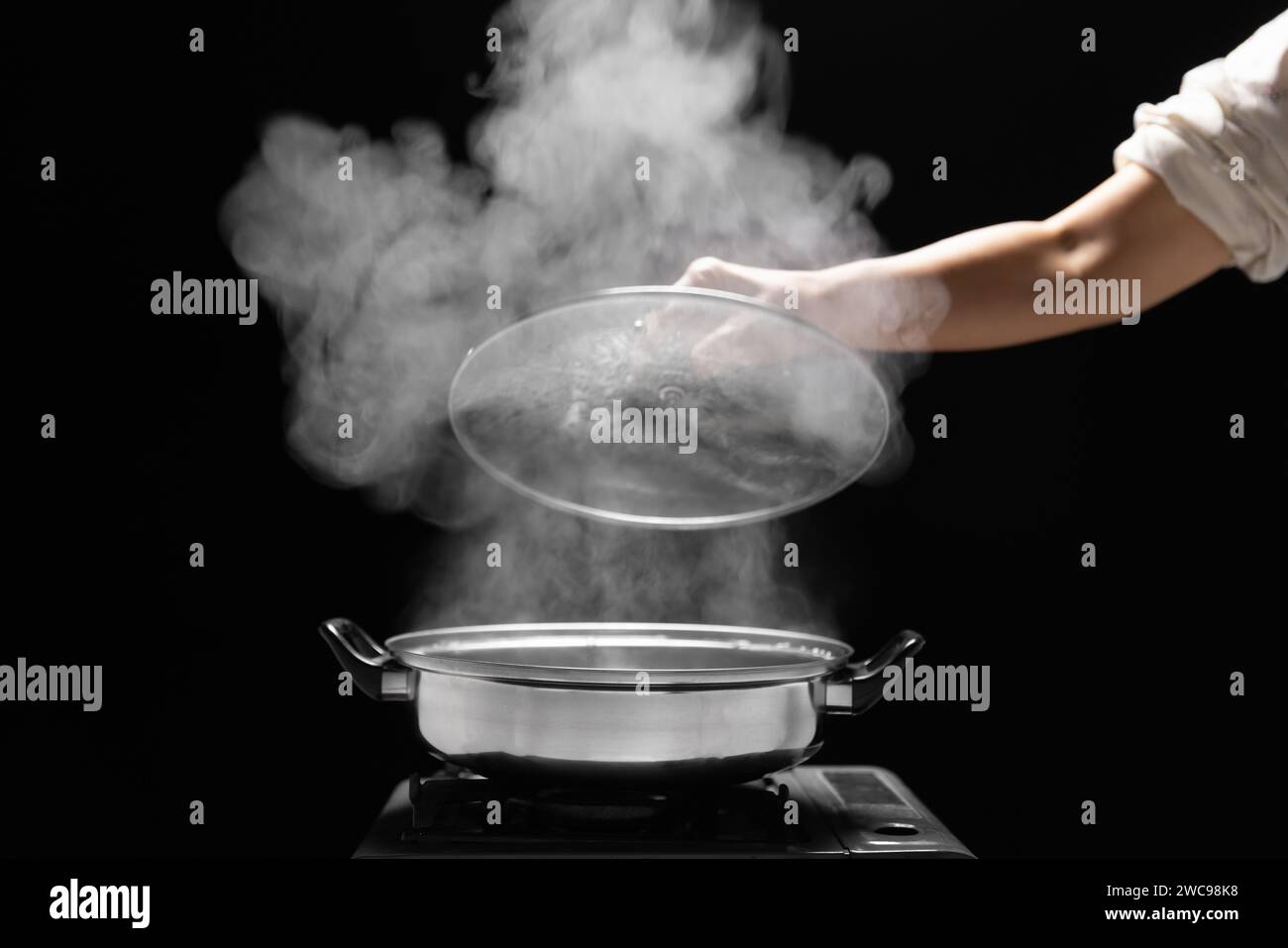Cuocere a vapore sulla pentola in cucina su sfondo scuro. Foto Stock