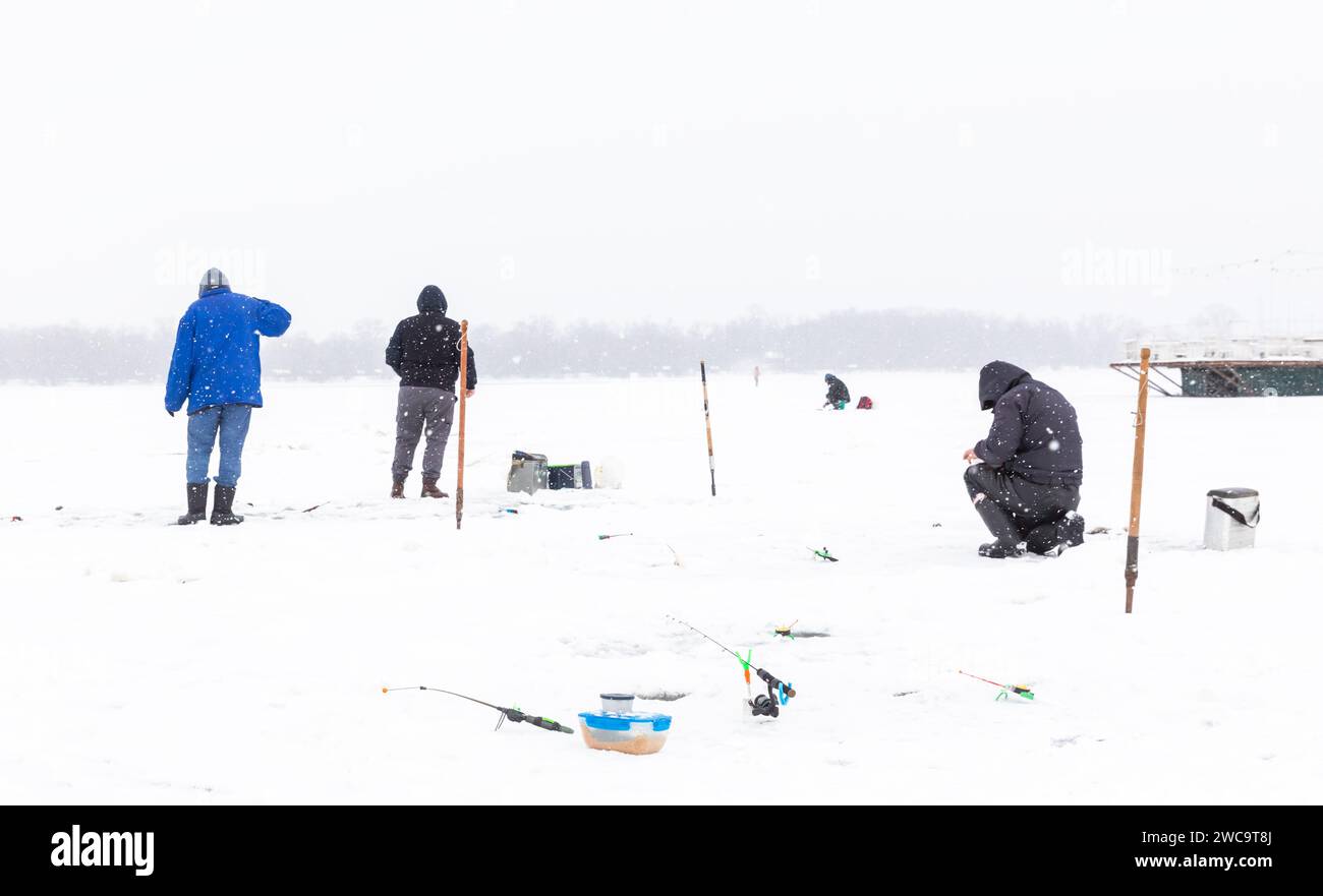 KIEV, UCRAINA - 14 gennaio 2024: Pesca sul ghiaccio sul fiume Dnieper a Kiev. Nonostante la guerra in corso contro l'Ucraina da parte delle federazioni russe, Kiev, la capitale dell'Ucraina, continua a vivere una vita pacifica. Foto Stock