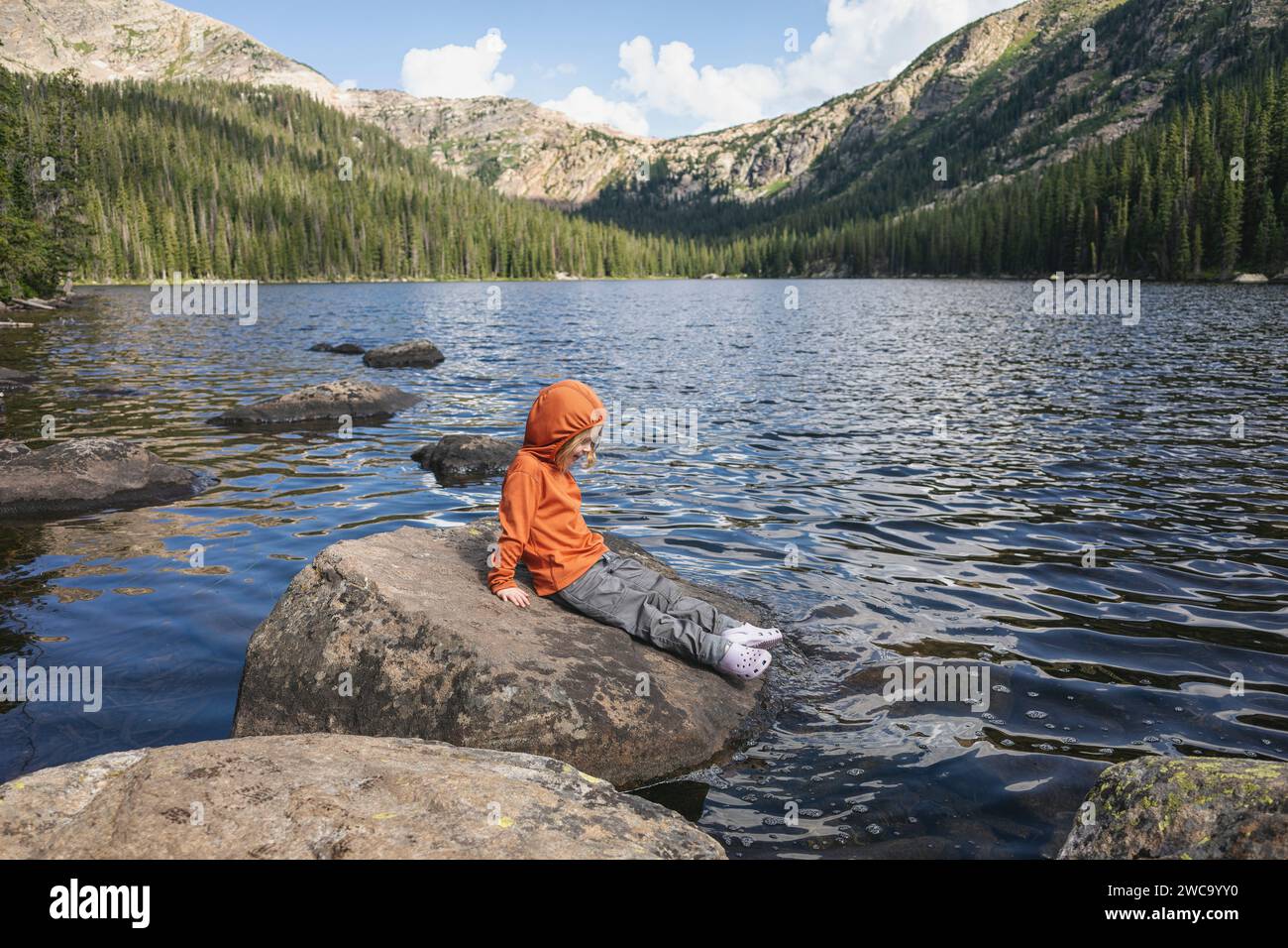 Bambini che esplorano la natura seduti su un masso vicino al lago Timberline Foto Stock