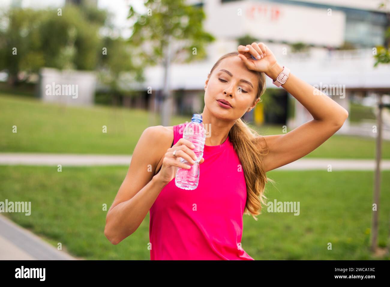 Donna che beve acqua dopo aver corso all'aperto, concetto di reidratazione Foto Stock