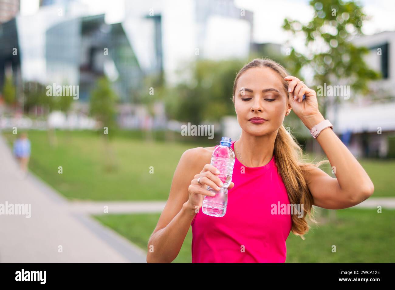 Donna che beve acqua dopo aver corso all'aperto, concetto di reidratazione Foto Stock