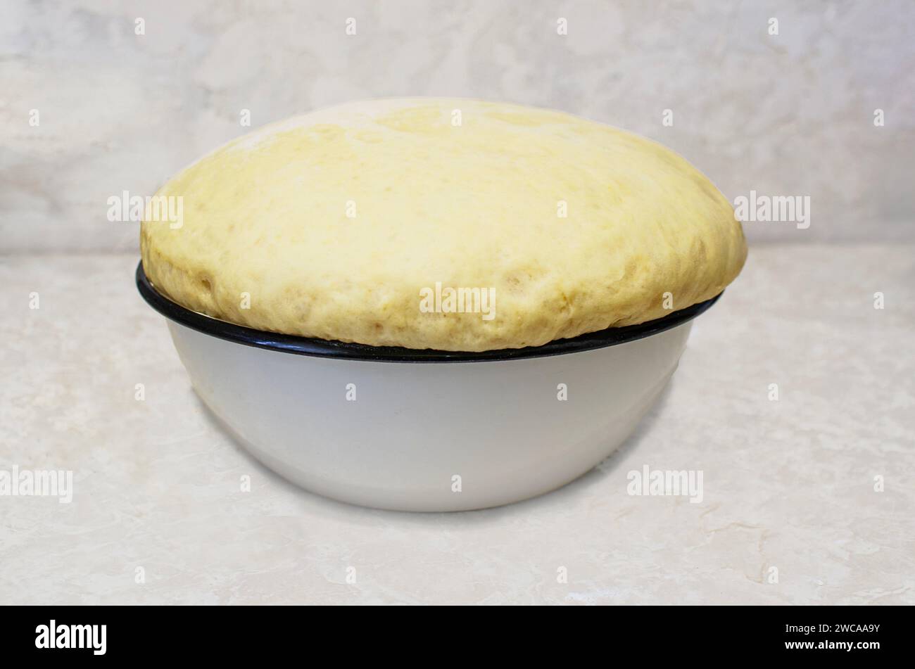 L'immagine mostra una ciotola di impasto che è aumentata in modo significativo, riempiendo e traboccando la ciotola. Questo segna i primi passi di successo nel productio Foto Stock