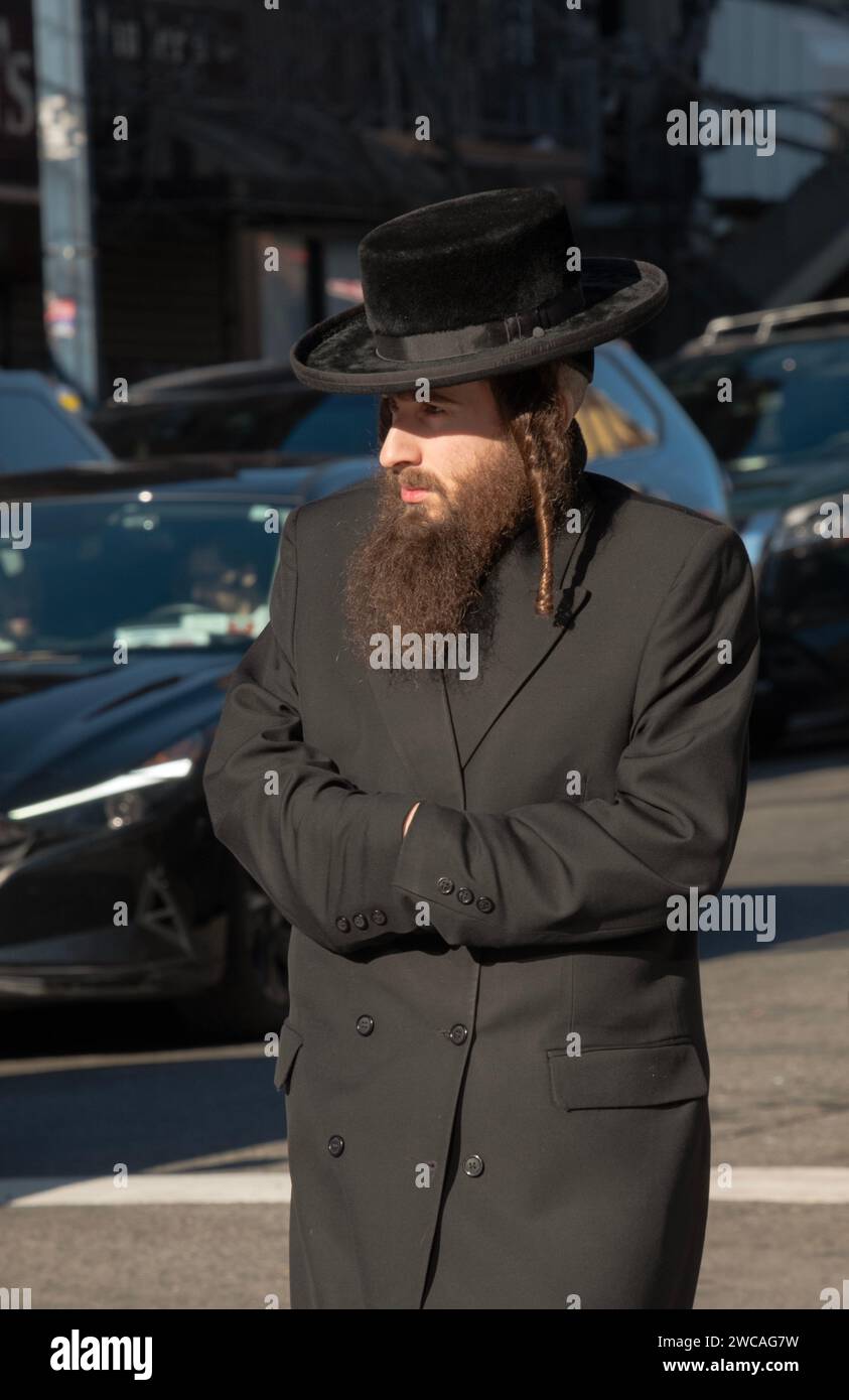 In una fredda giornata invernale un ebreo chassidico cammina su Lee Avenue usando le maniche invece dei guanti. A Williamsburg, Brooklyn, New York. Foto Stock