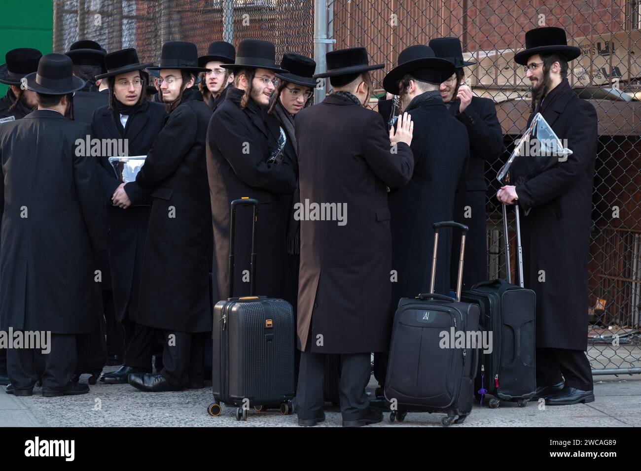 Un gruppo di studenti ebrei ortodossi aspetta un autobus per trasportarli in una classe di Talmud dall'altra parte di Brooklyn, New York. Foto Stock